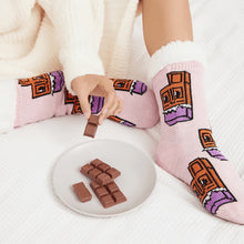 Load image into Gallery viewer, The Foozie™ Chocolate slipper socks, worn on a white bed beside a plate of chocolate