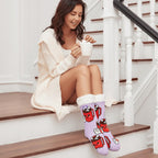 The Foozie™ Marshmallow slipper socks, worn by a woman sitting on the stairs with a mug