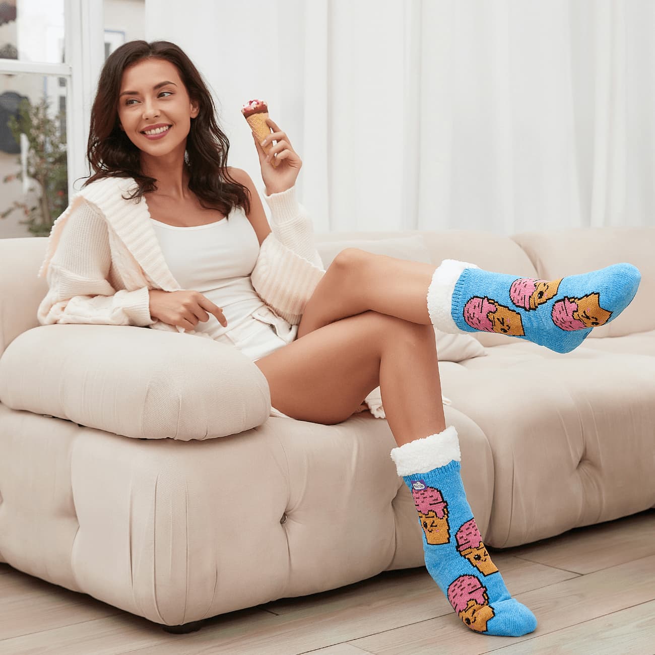 The Foozie™ Ice Cream slipper socks, worn by a woman on the sofa holding an ice cream cone